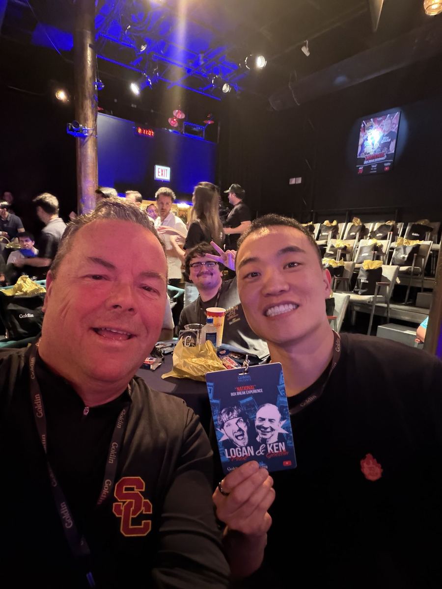 Two members of the NOVL team holding a Logan Paul and Ken Goldin box break credential.